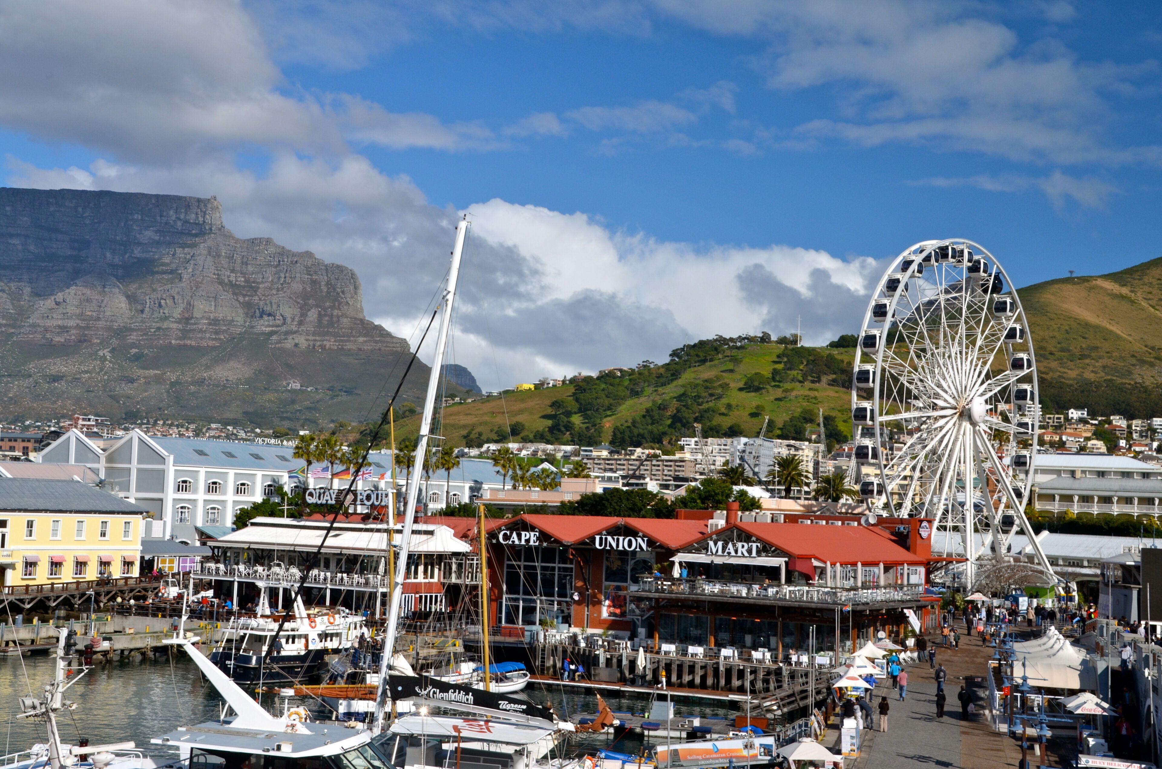 Un puerto con barcos, una noria y edificios con señalización 'CAPE UNION'.