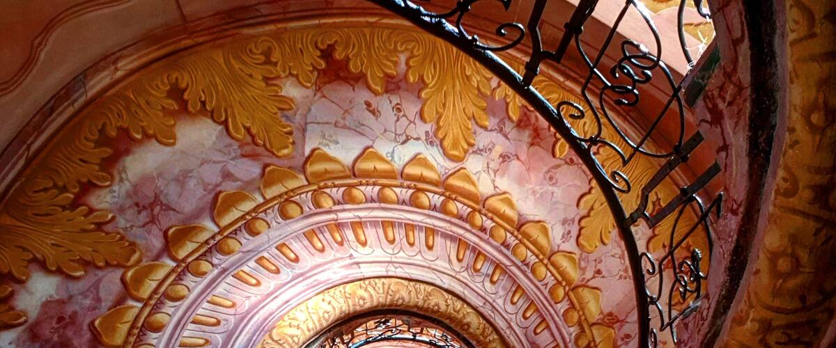 A spiral staircase with ornate golden and pink floral patterns.