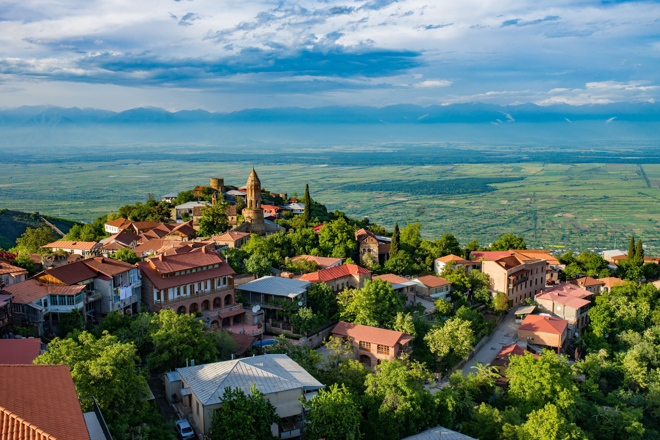A village with historic architecture, a prominent church, and a mountainous backdrop.