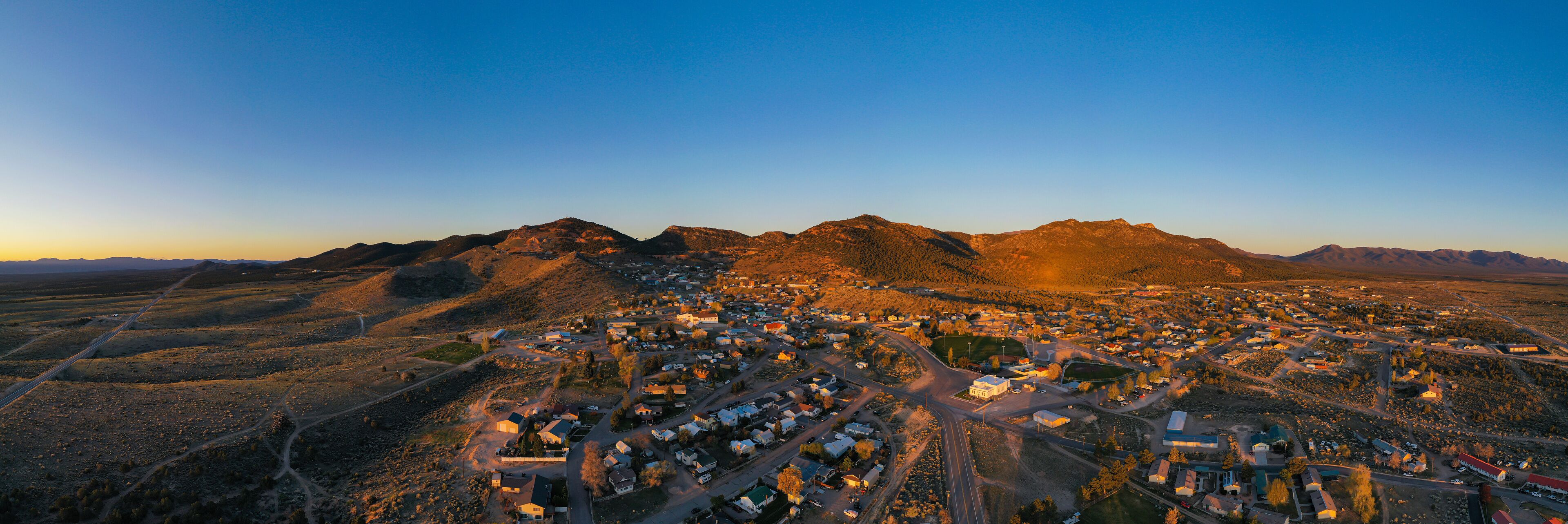 An aerial view of a town nestled between mountains during sunset.