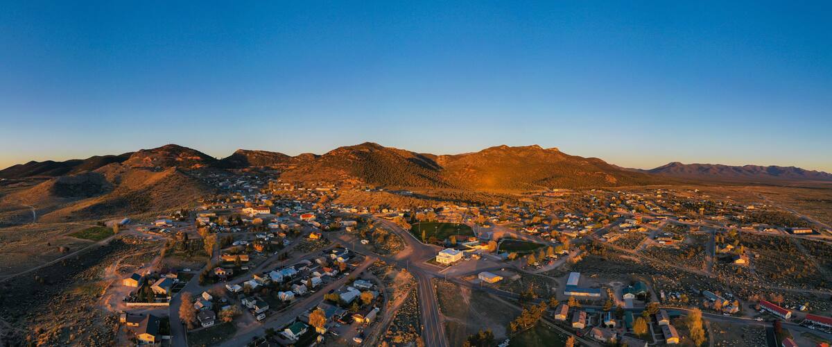 An aerial view of a town nestled between mountains during sunset.
