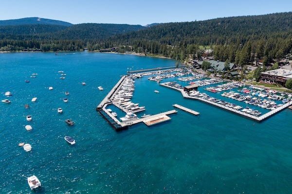 Aerial view of a bustling Lake Tahoe marina. Many boats are docked, and the surrounding area has shops and restaurants. Perfect for a vacation destination. Tahoe City, California, USA