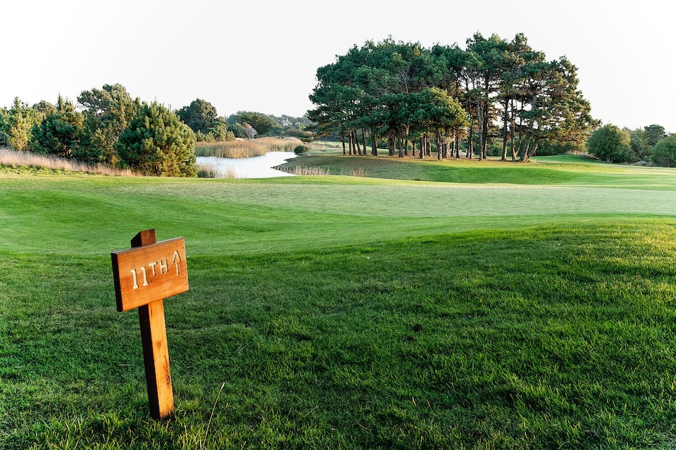 Camp de golf amb un senyal de fusta que indica el forat 11.