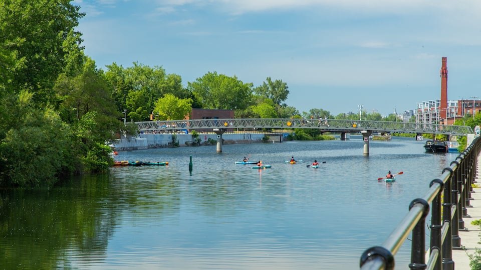 A river with kayakers, a bridge, and a red tower in the background.