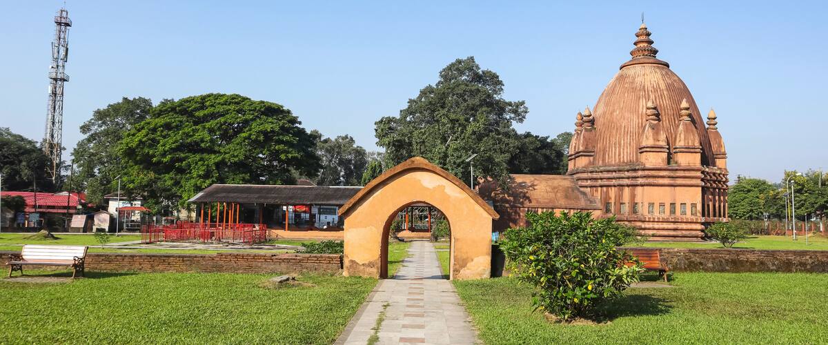 A temple with a large dome and an archway in a grassy area.