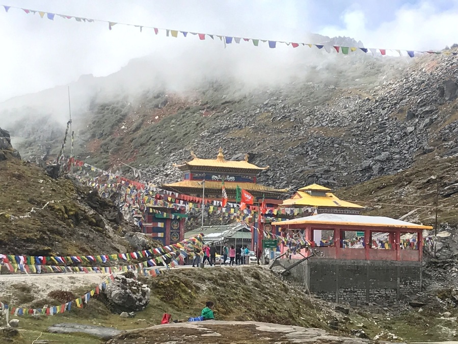 A mountainous area with a traditional building and prayer flags.