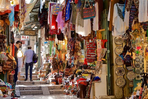 Eine schmale Marktstraße mit verschiedenen Ständen, an denen Schmuck, Textilien und andere Waren verkauft werden.