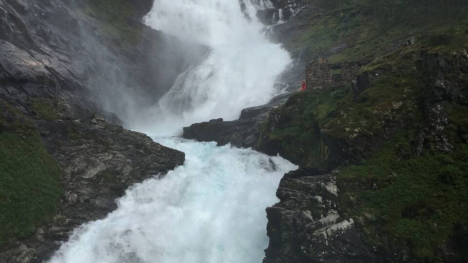 Ett mäktigt vattenfall som störtar ner i en bergig ravin, omgivet av frodig grönska.