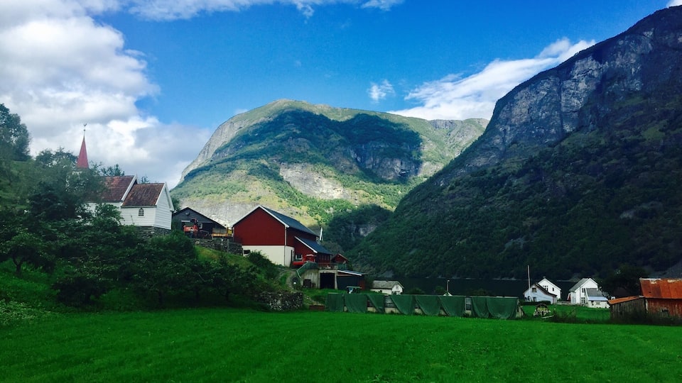 Ett kuperat landskap med en kyrka, en röd ladugård och en grön äng.