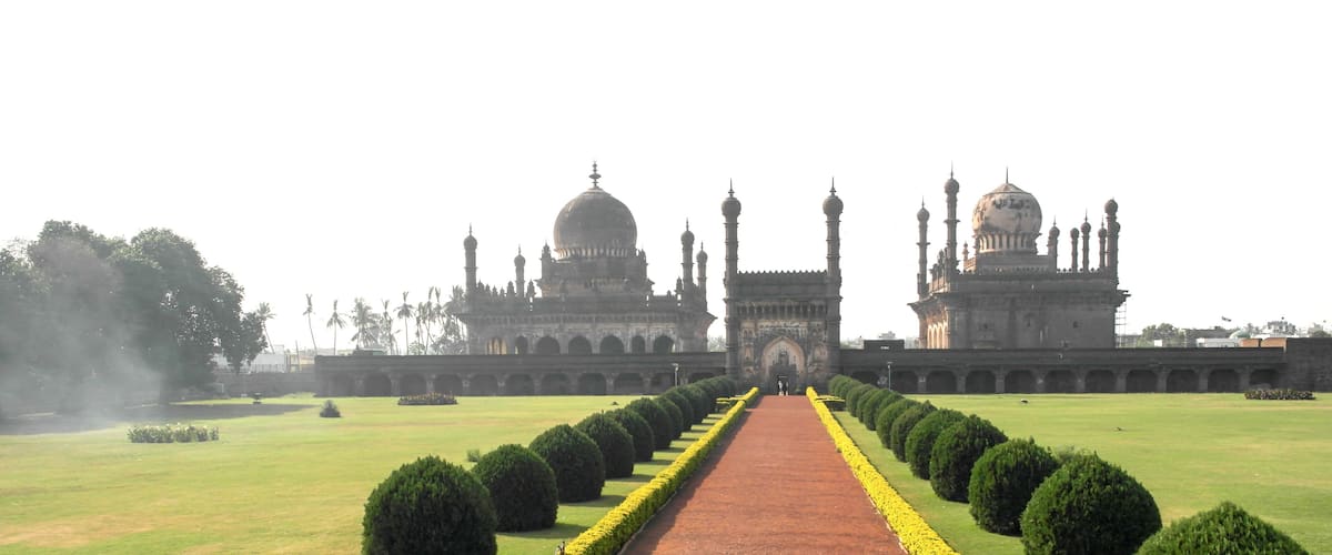 A grand building with domes and minarets, a central pathway, and well-manicured lawns.