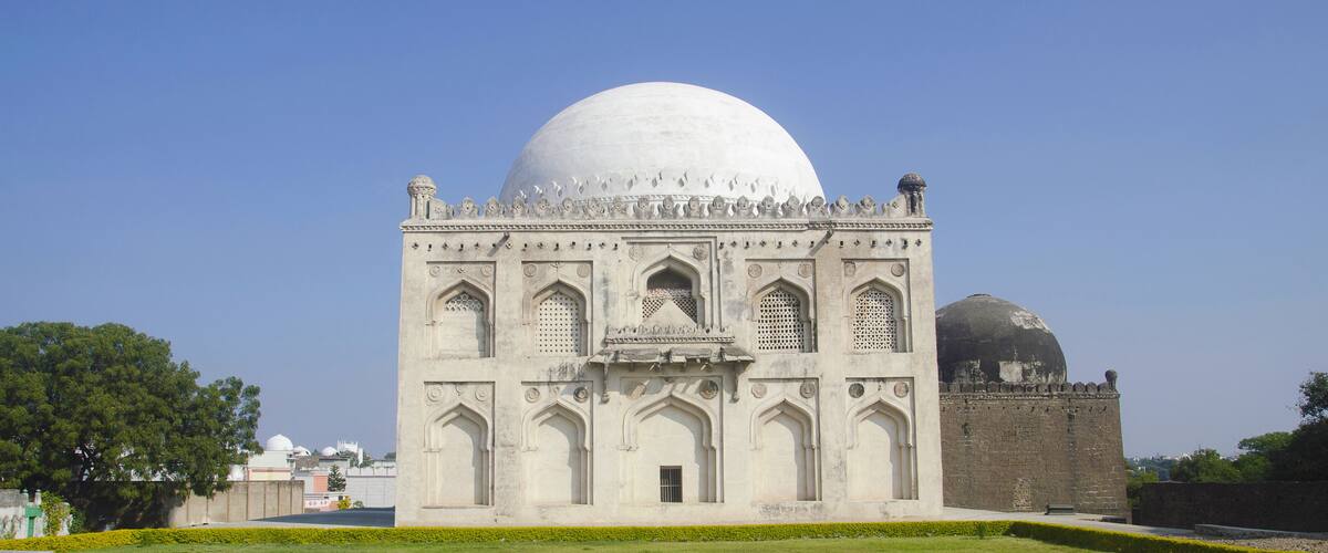 A large white dome structure with intricate architectural details and a smaller dome in the background.