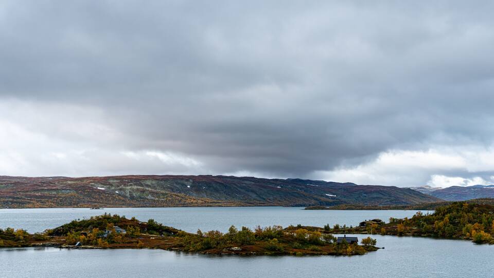 A lake surrounded by hills and autumn-colored trees.