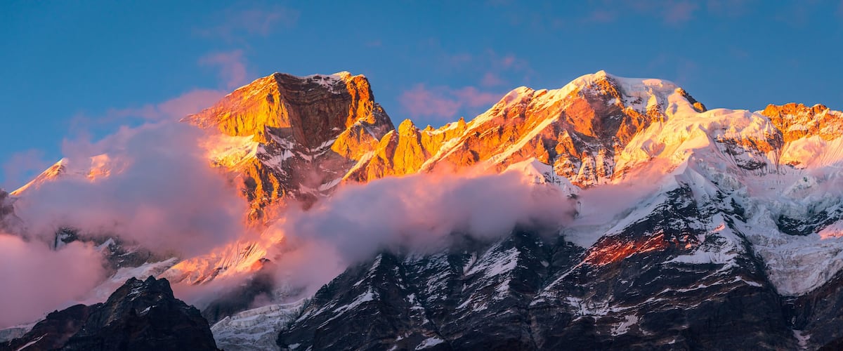 A mountain range with snow-capped peaks and a clear blue sky.