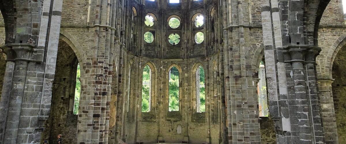 An interior of a Gothic-style cathedral with high vaulted ceilings, large arched windows, and stone columns.