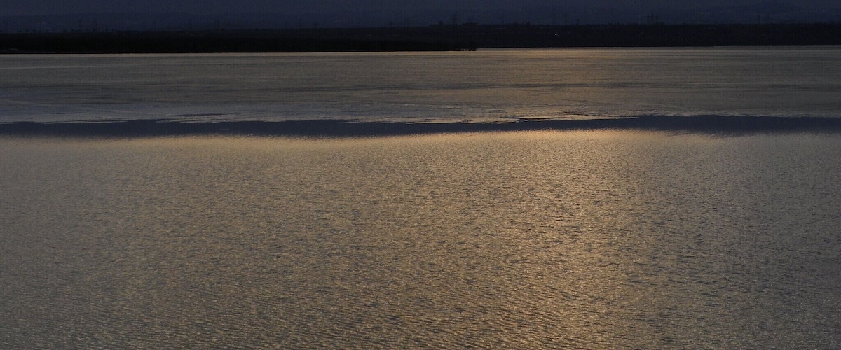 A body of water with a cloudy sky and a distant shoreline.