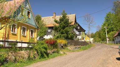 A rural road with colorful houses, a wooden fence, and a clear blue sky.