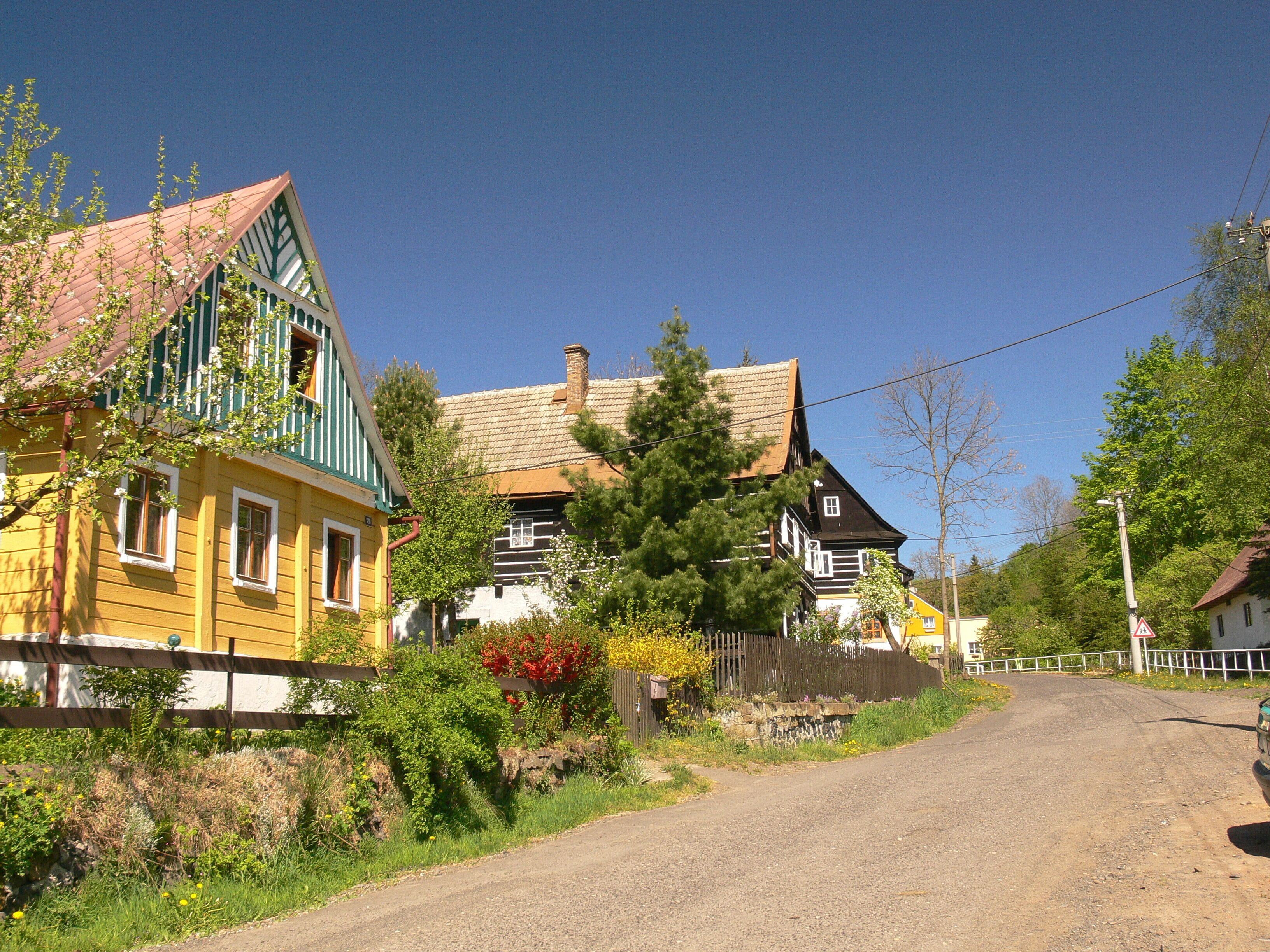 A rural road with colorful houses, a wooden fence, and a clear blue sky.