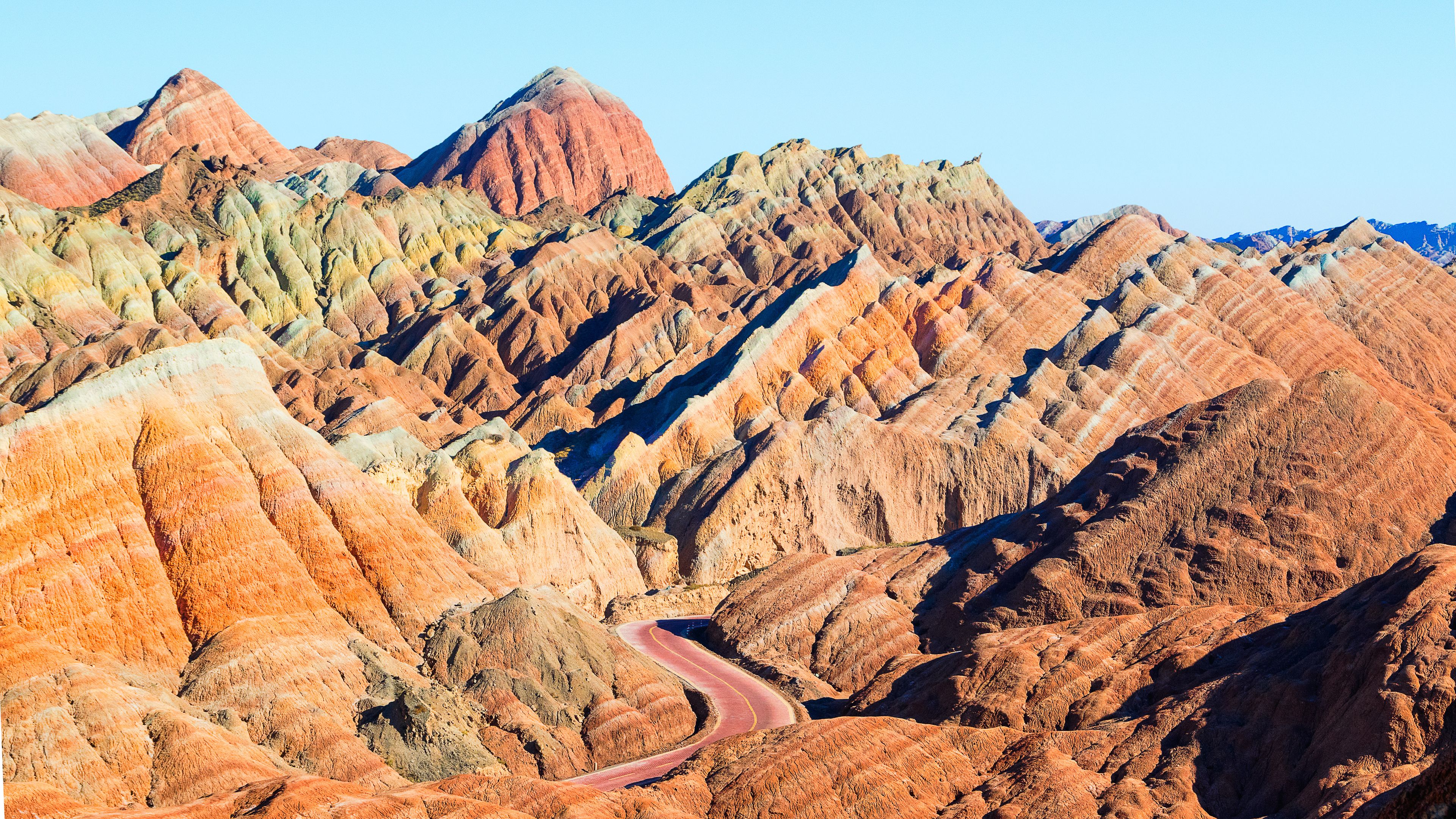 A winding road through a colorful, rugged mountain landscape.