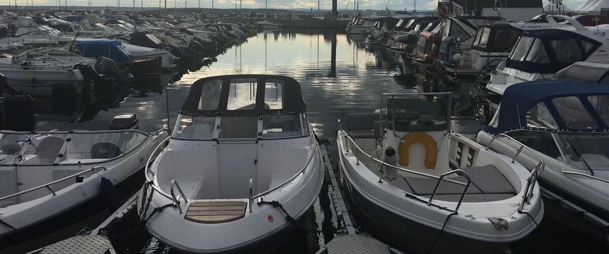 A marina with several boats docked in calm waters under a cloudy sky.