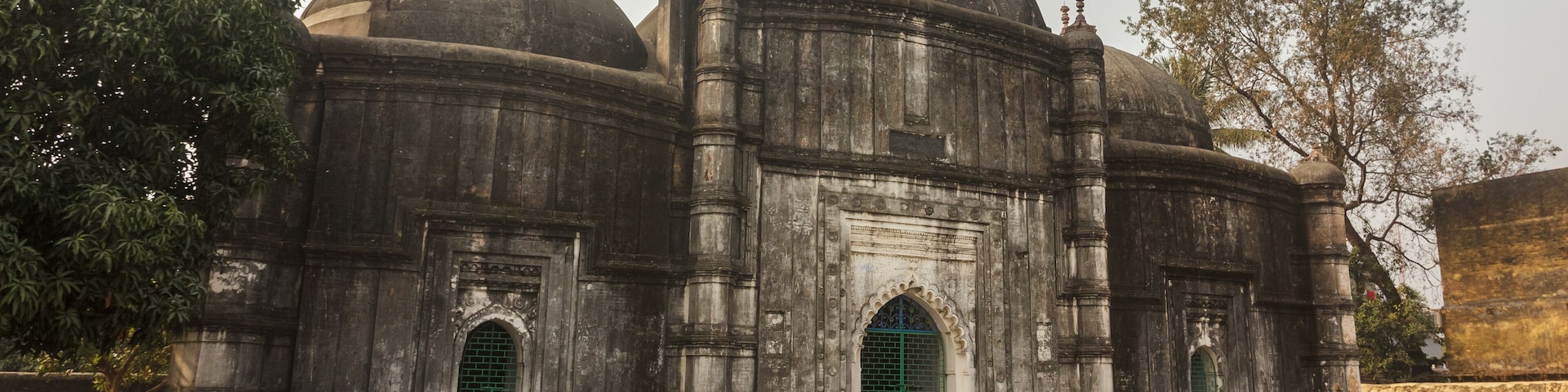 An old stone building with domes and arched doorways.