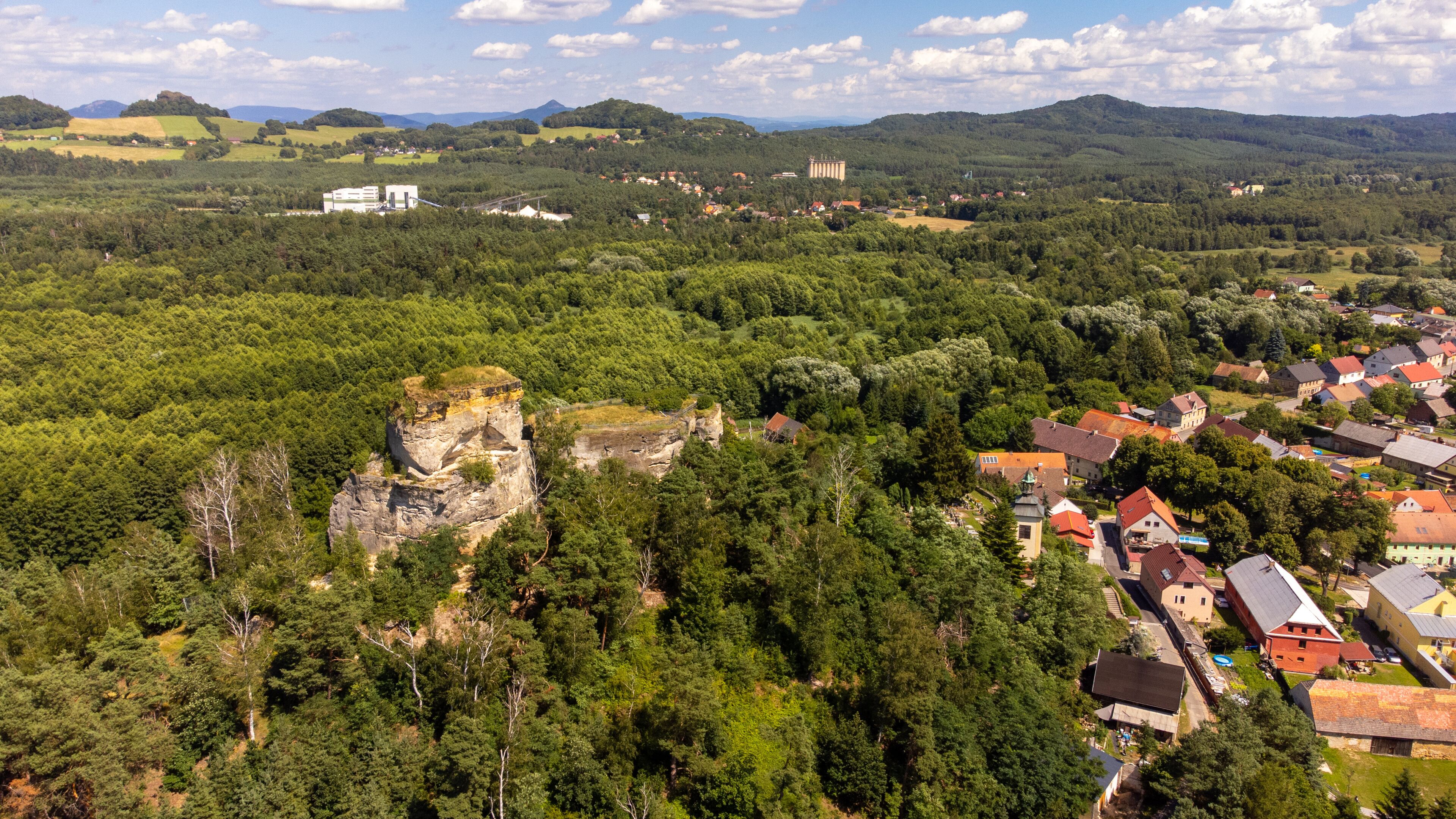 A town nestled in a valley with a prominent rock formation and surrounding greenery.