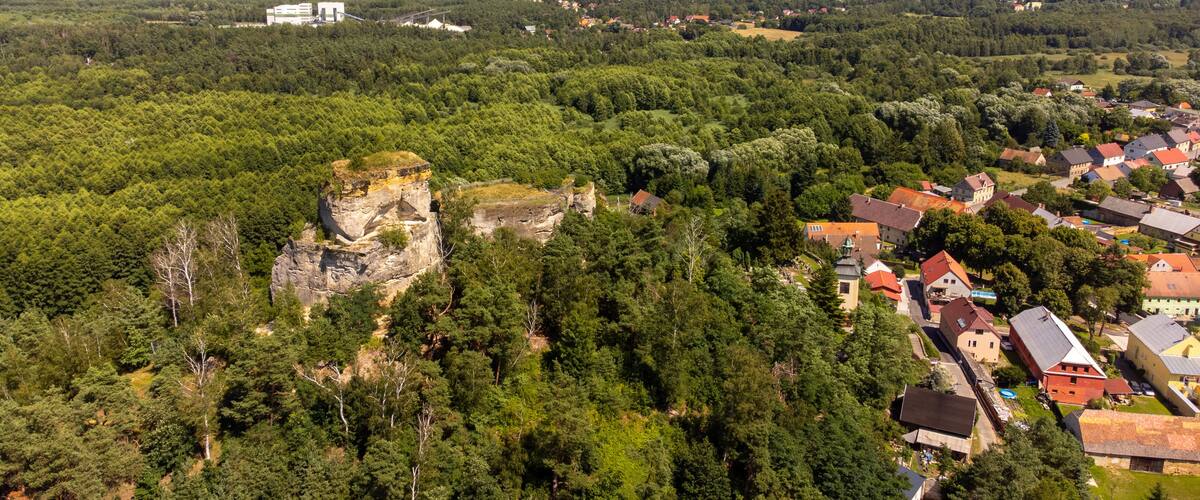 A town nestled in a valley with a prominent rock formation and surrounding greenery.