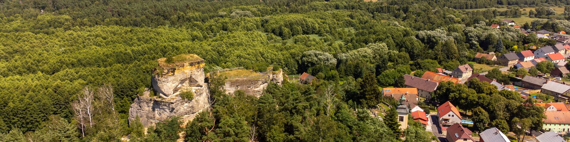A town nestled in a valley with a prominent rock formation and surrounding greenery.