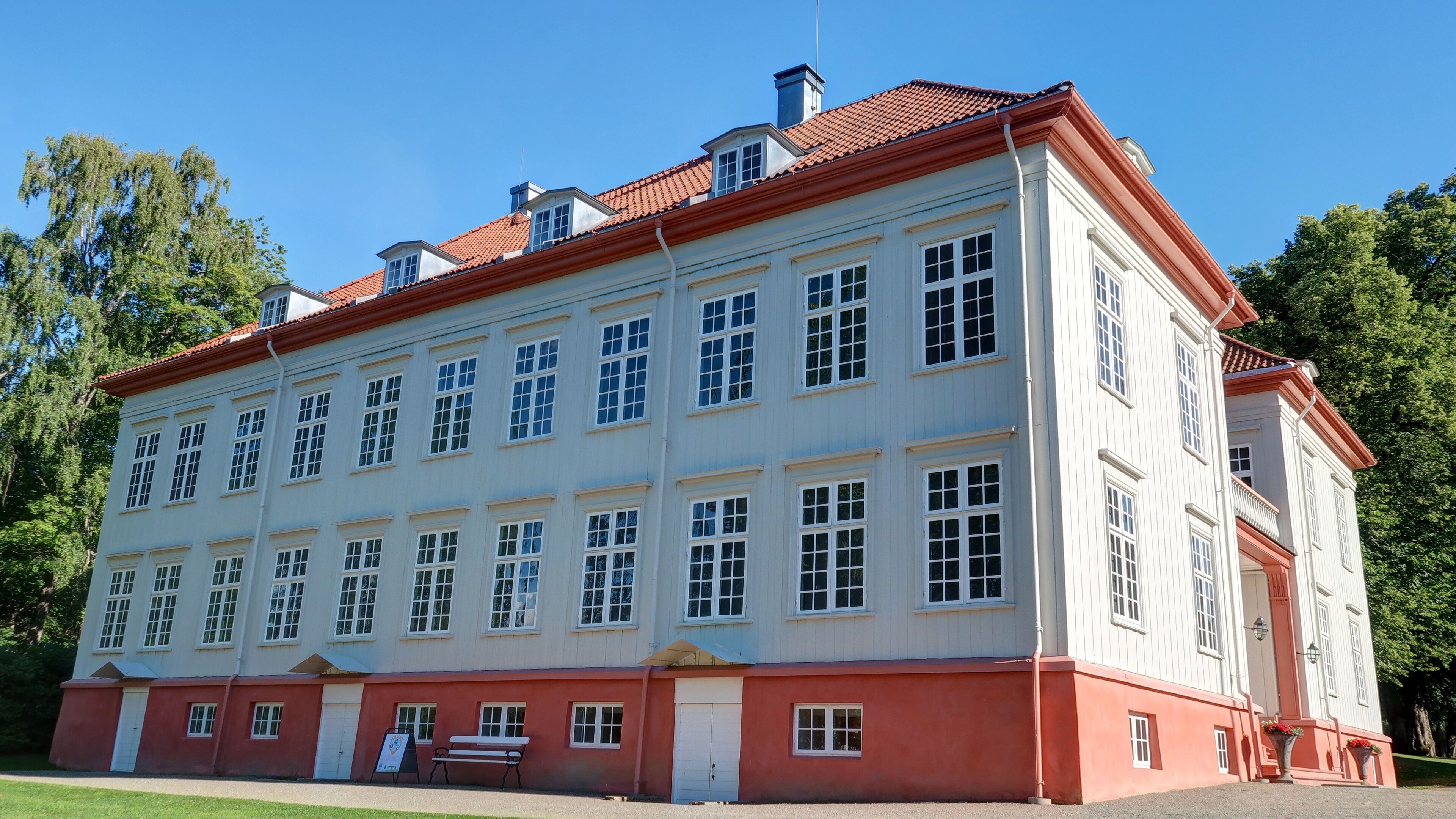 A large, white building with red trim and multiple windows.