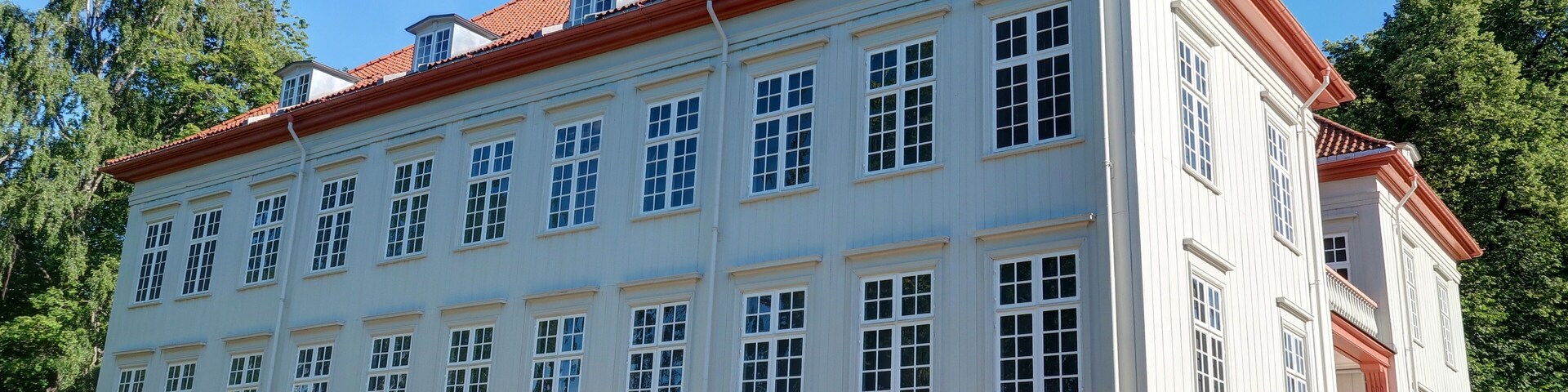 A large, white building with red trim and multiple windows.