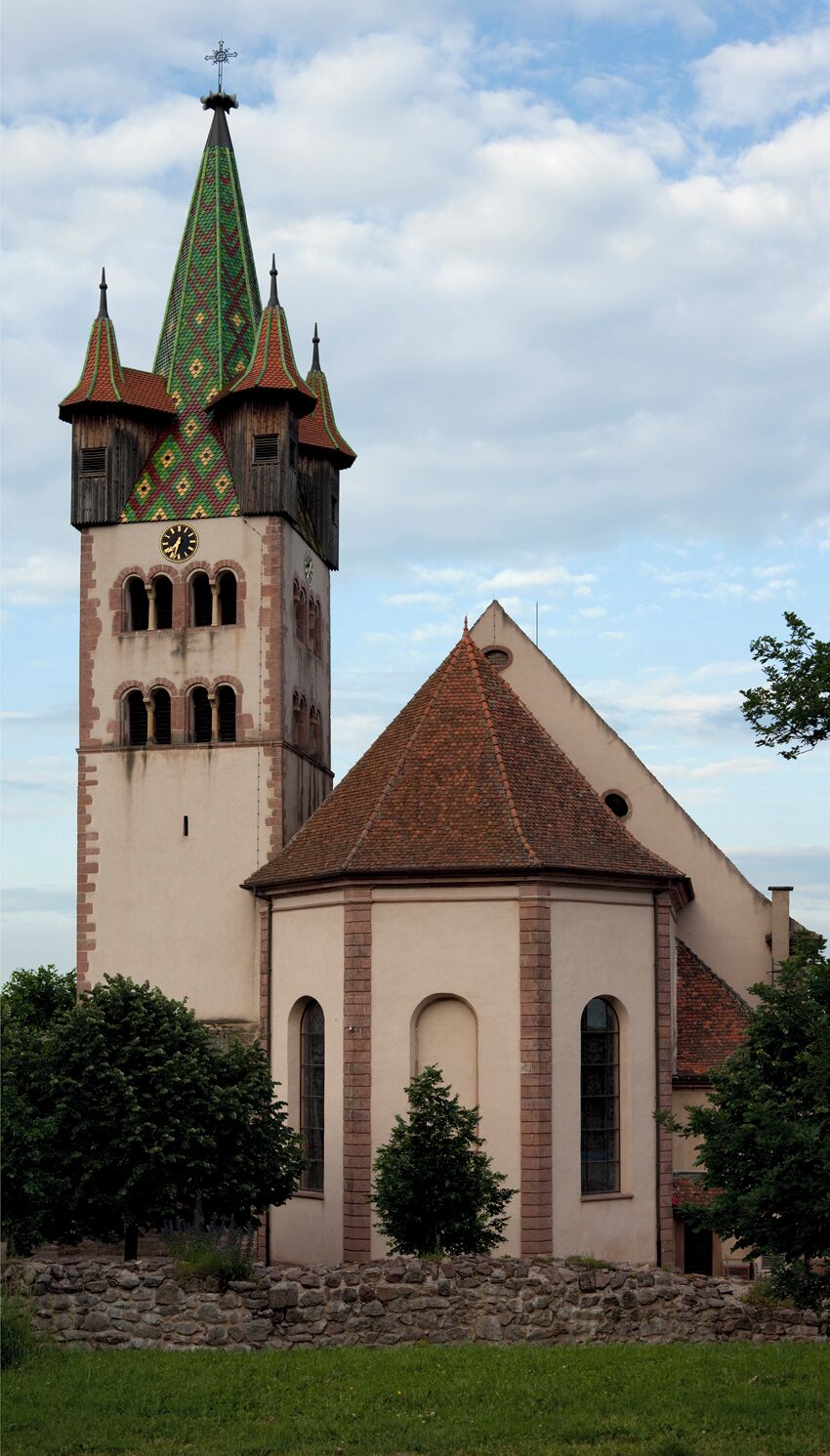 A church with a clock tower and a smaller building with a red roof.