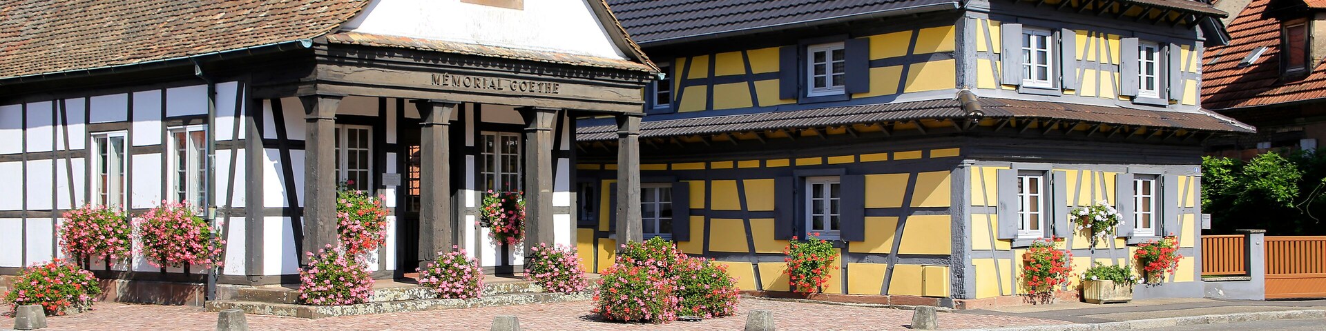Un edificio tradicional con entramado de madera, con un letrero que dice "KLEINER GOETHE" y macetas con flores en la acera.
