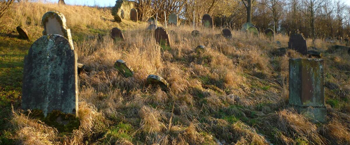 A cemetery with numerous headstones scattered across a grassy hill.