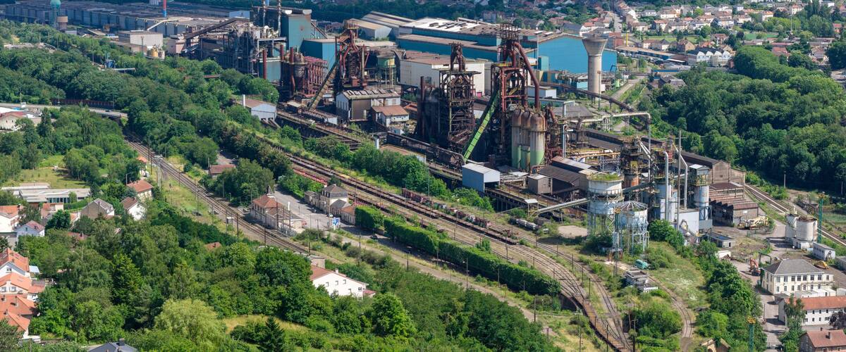 An industrial complex with multiple buildings, large storage tanks, and extensive railway tracks.