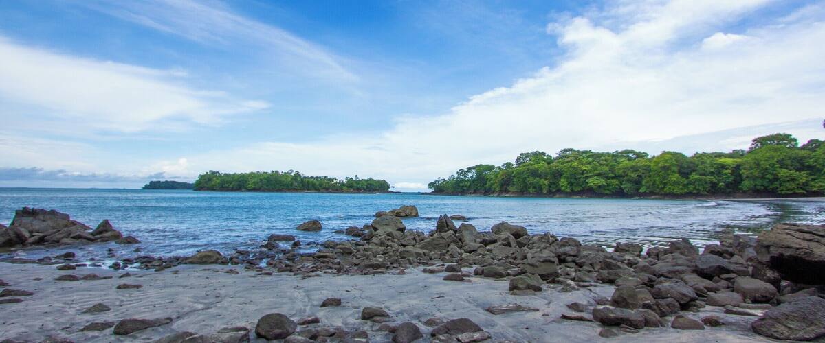 A rocky shoreline with a clear blue sky and calm sea.