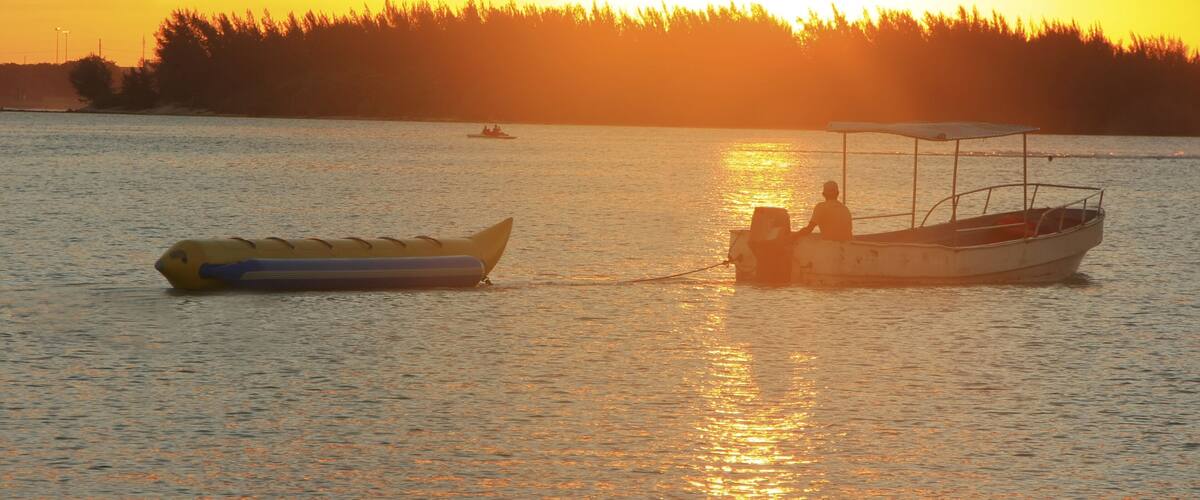 A sunset over a calm body of water with a small boat and a yellow raft.