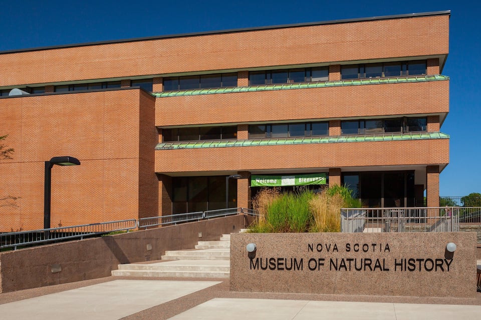 The Nova Scotia Museum of Natural History building with a brick facade, green awnings, and a sign welcoming visitors.