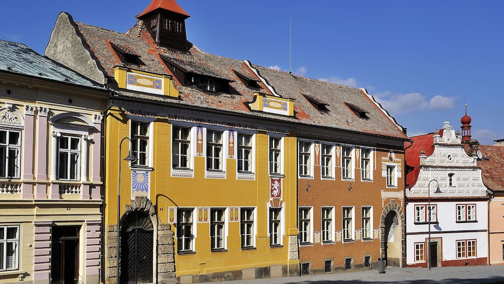 Un bâtiment jaune avec un toit rouge et un bâtiment blanc surmonté d’un dôme rouge.