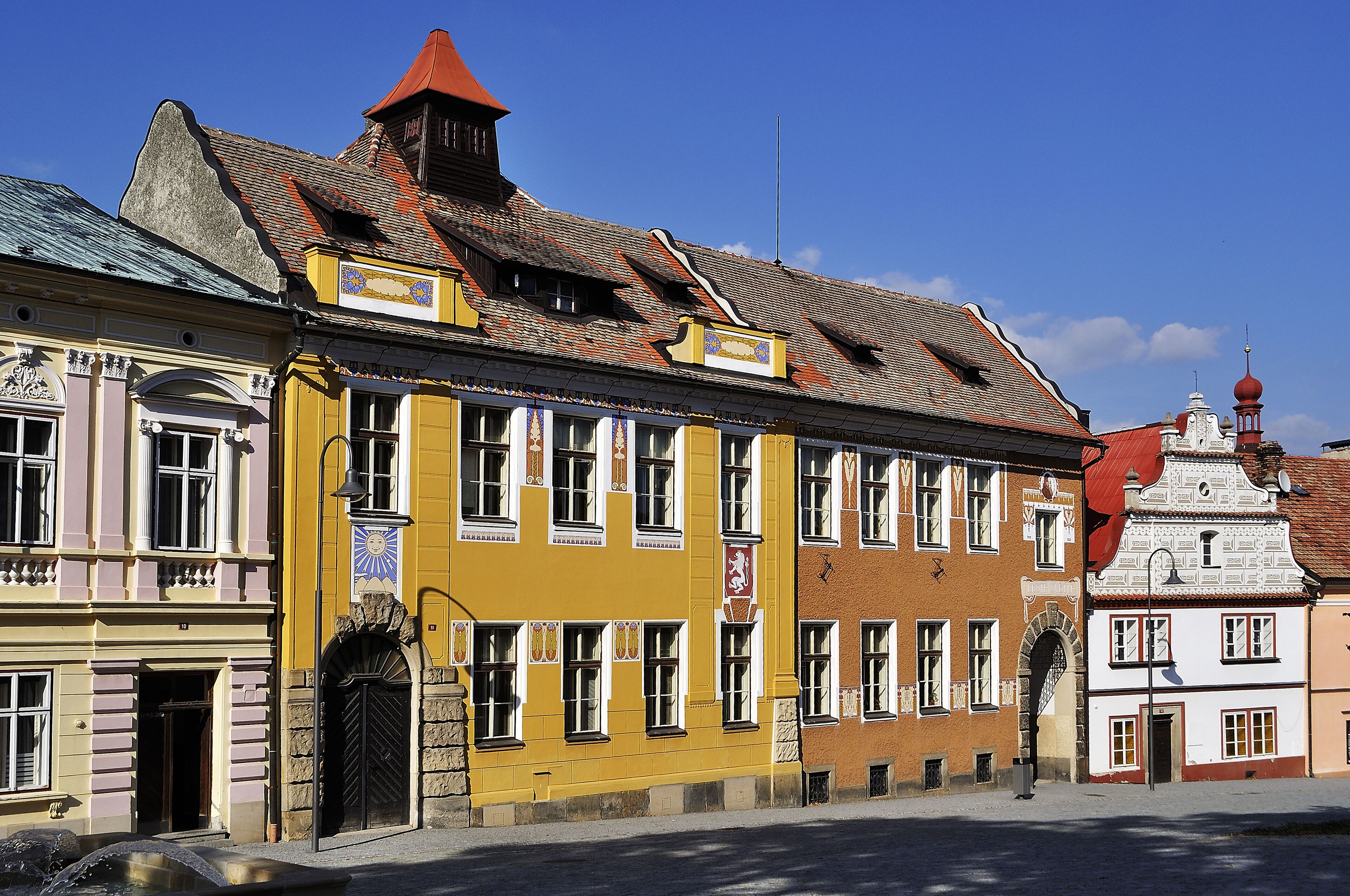 A yellow building with a red roof and a white building with a red dome.