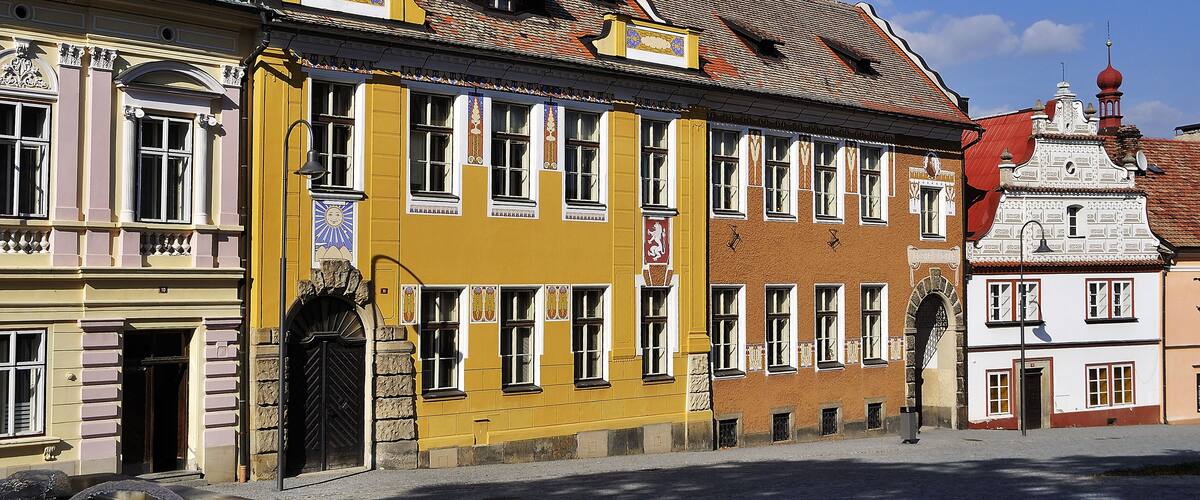 A yellow building with a red roof and a white building with a red dome.