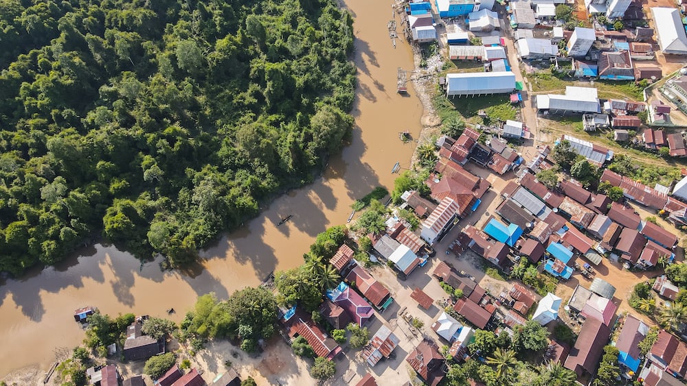Residential center on the edge of a river and forest in a rural area, on the edge of a cross-regional road, in East Kotawaringin Regency, Central Kalimantan, Indonesia, seen from an aerial view.