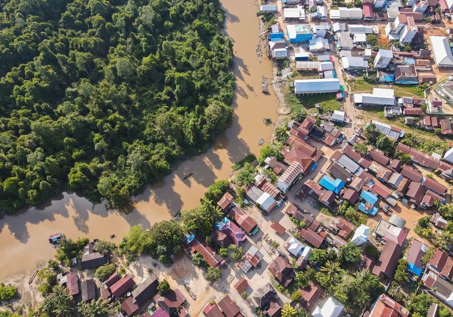 Residential center on the edge of a river and forest in a rural area, on the edge of a cross-regional road, in East Kotawaringin Regency, Central Kalimantan, Indonesia, seen from an aerial view.