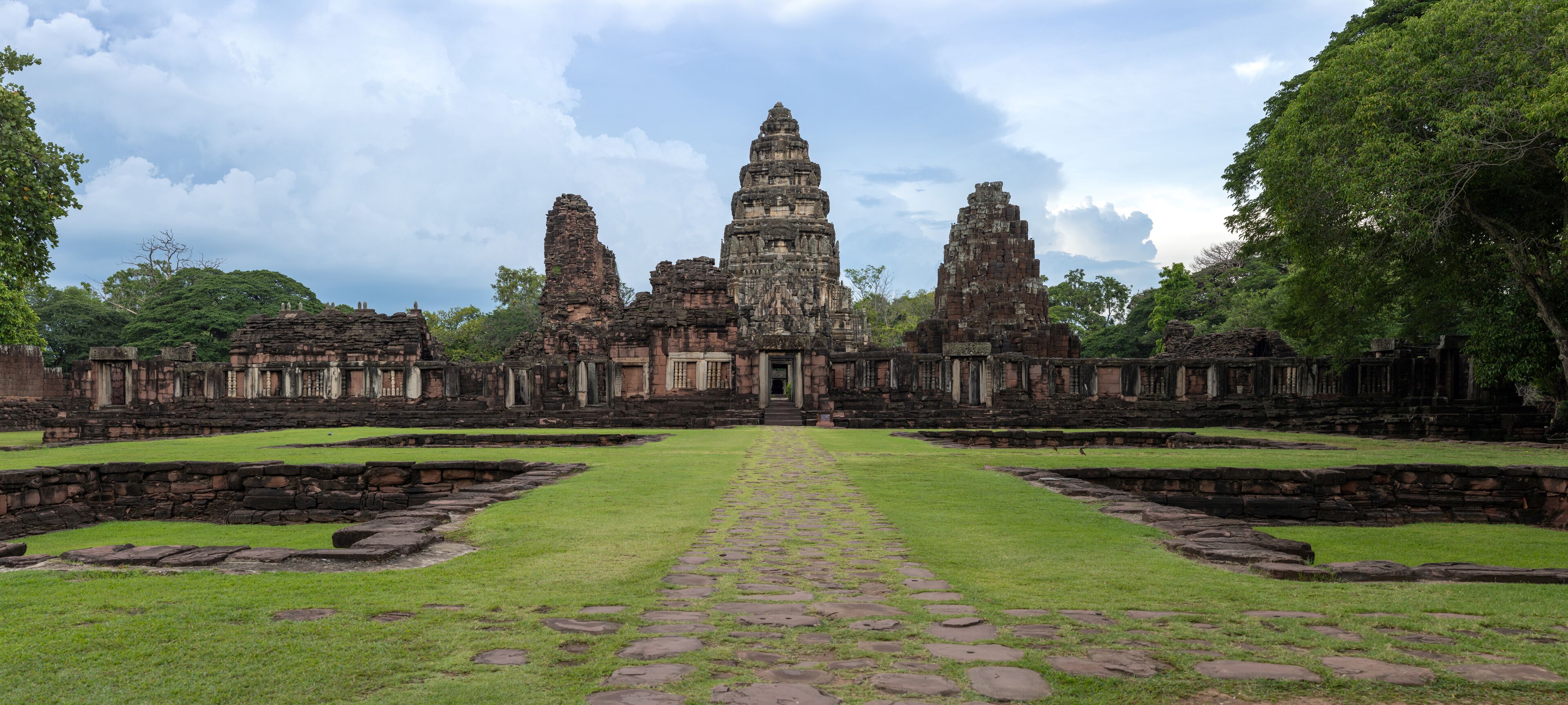 An ancient temple complex with a central tower, surrounded by stone walls and pathways.