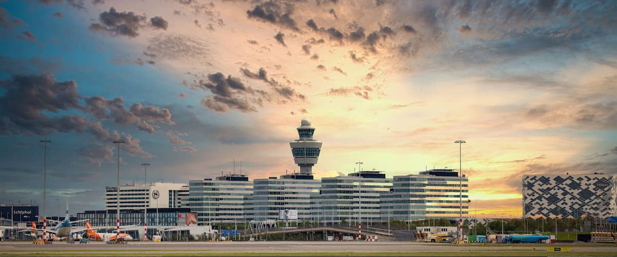 An airport with a control tower, terminal buildings, and a sunset sky.