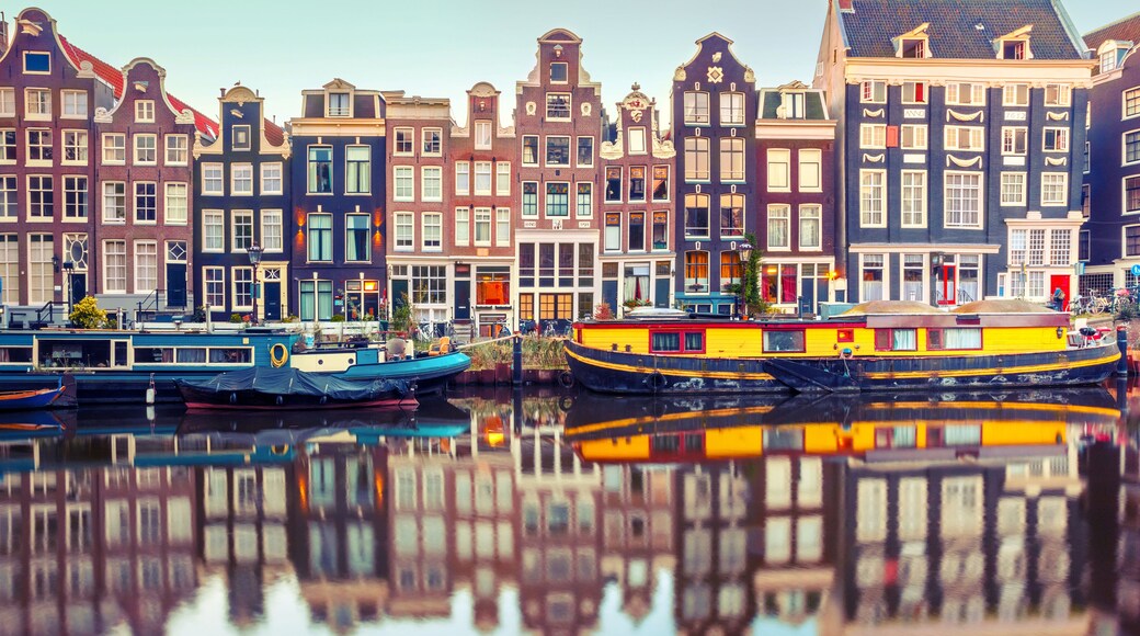 Amsterdam canal Singel with typical dutch houses and houseboats during morning blue hour, Holland, Netherlands. Used toning