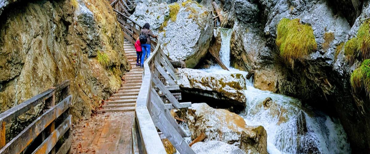 A wooden walkway leading through a rocky canyon with a waterfall.