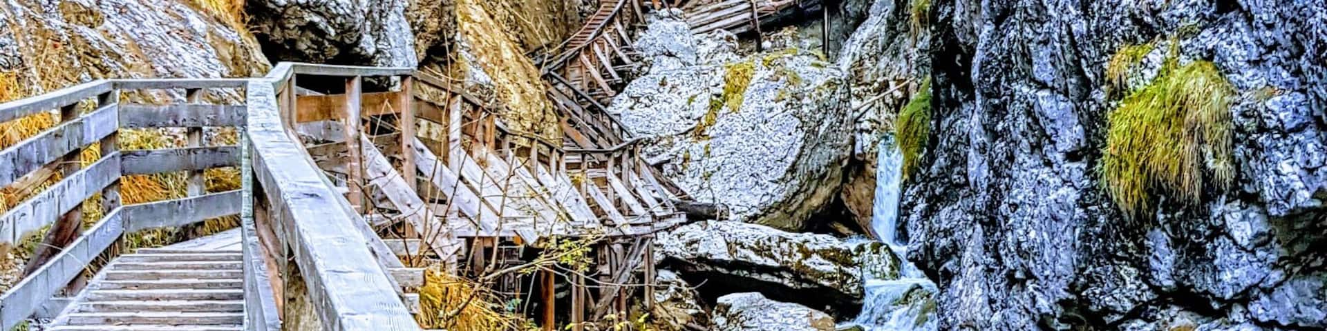 A wooden bridge over a rocky stream with moss-covered rocks.
