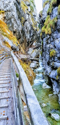 A wooden bridge over a rocky stream with moss-covered rocks.