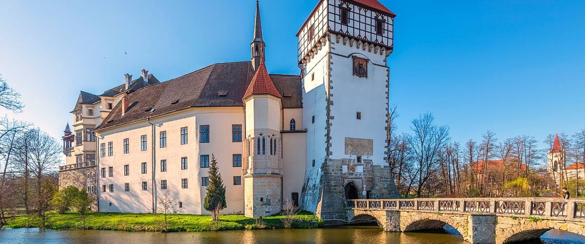 A castle with a red-tiled roof and a tall tower with a spire.