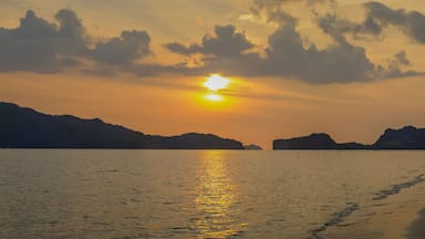 view panorama seaside evening on long beach of limestone mountain in the sea with yellow sun light and cloudy sky background, sunset at Pak Bara Beach, La-ngu District, Satun, southern Thailand.