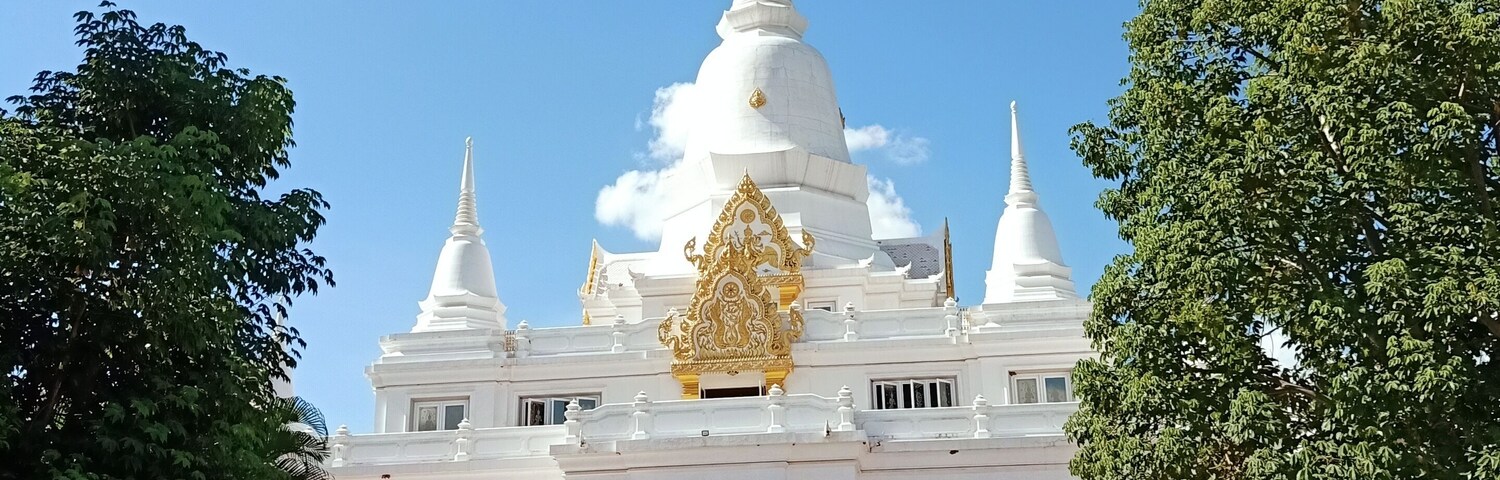Un templo blanco con una aguja dorada y una escalera que conduce a la entrada.